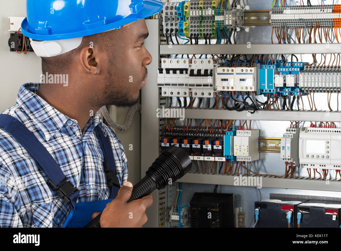 I giovani africani tecnico maschio analizzando scatola fusibili con la torcia elettrica Foto Stock