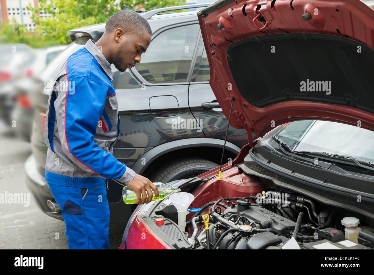 Giovane africana meccanico Versando olio lubrificante nel motore per auto Foto Stock