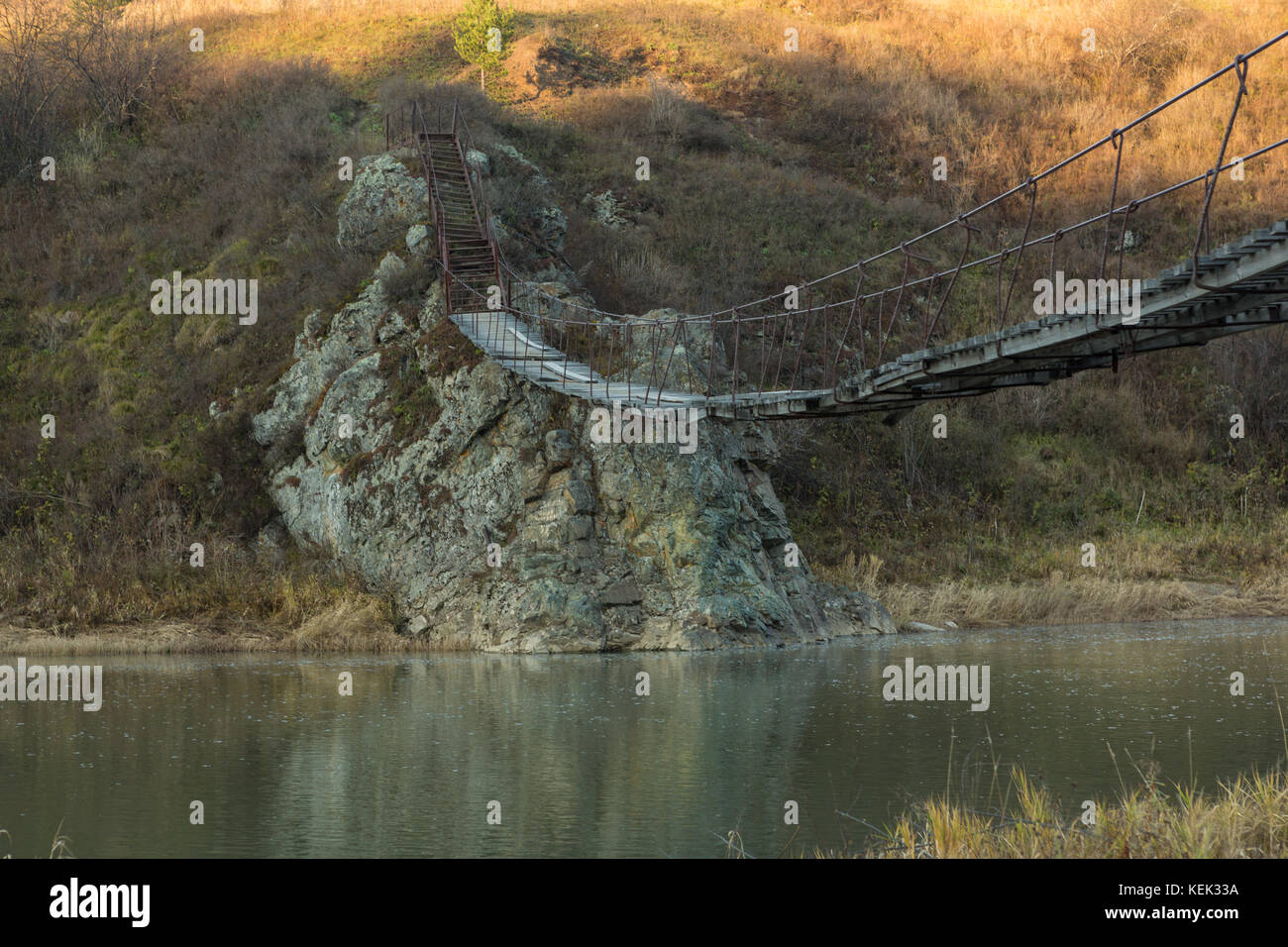 Il molto vecchia passerella pedonale sospesa su un piccolo fiume. Foto Stock