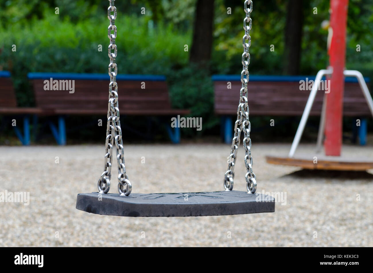 Immagine di un bambini swing con catene di ferro su un parco giochi durante un autunnale di giorno di pioggia Foto Stock