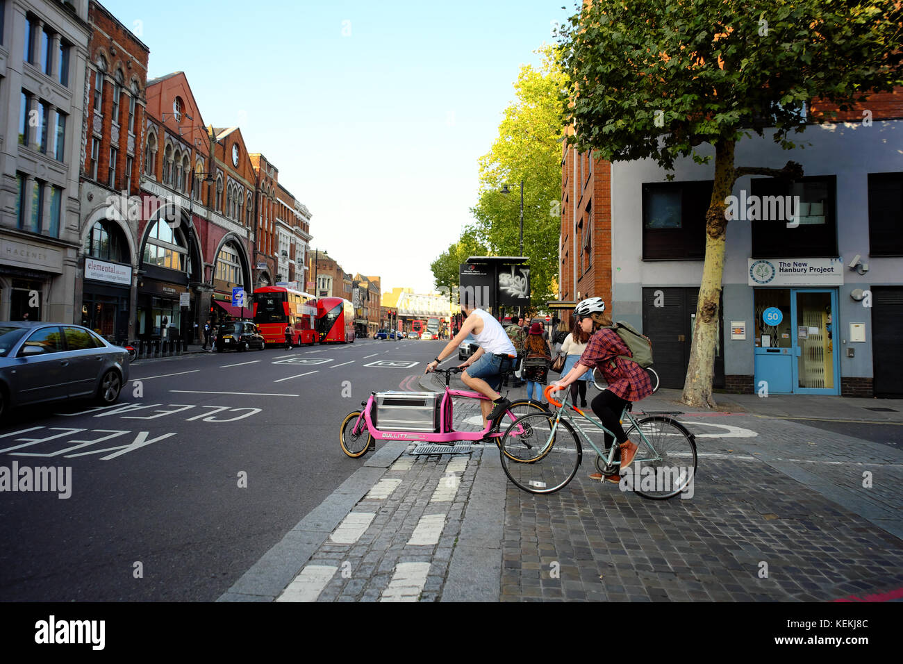 Uomo su una stirata Rosa Consegna biciclette e donna su un corridore in attesa di road unione a Londra in Inghilterra Foto Stock