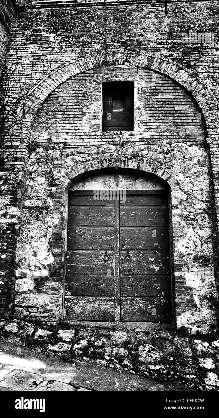 Porta di legno con un muro di mattoni in Toscana, Italia Foto Stock