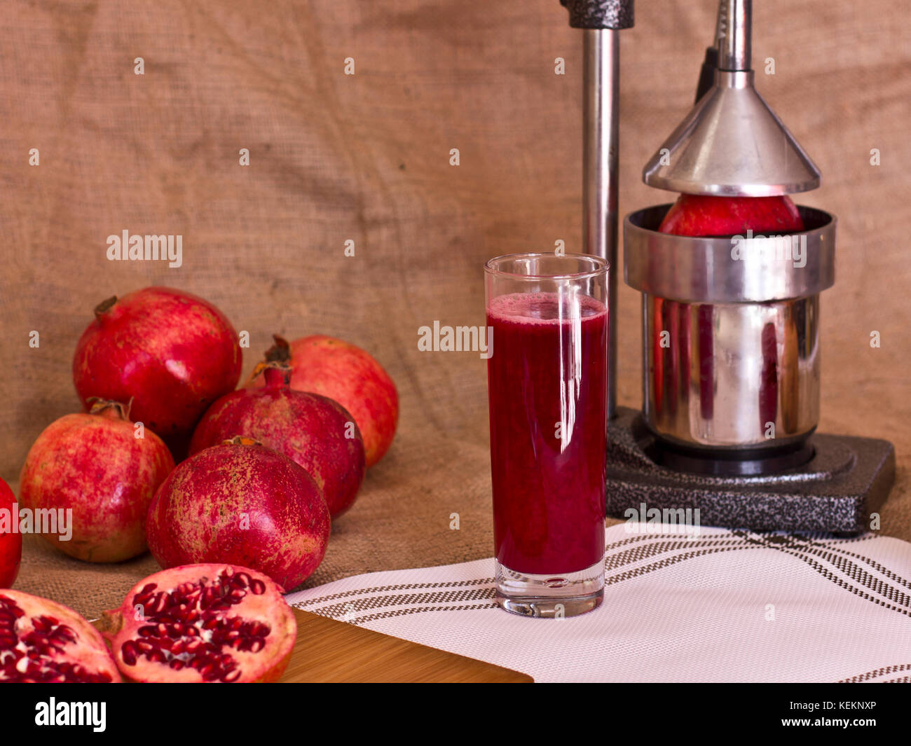 Il succo di melograno in un bicchiere accanto al taglio pomergranat su una  scheda. metallo centrifuga premere dietro Foto stock - Alamy