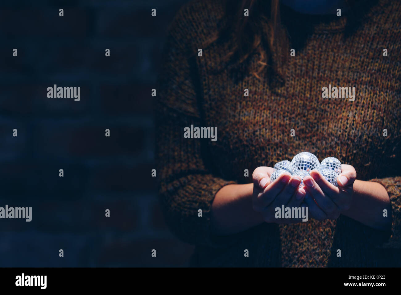 Close up della donna azienda discoballs sotto un faretto Foto Stock