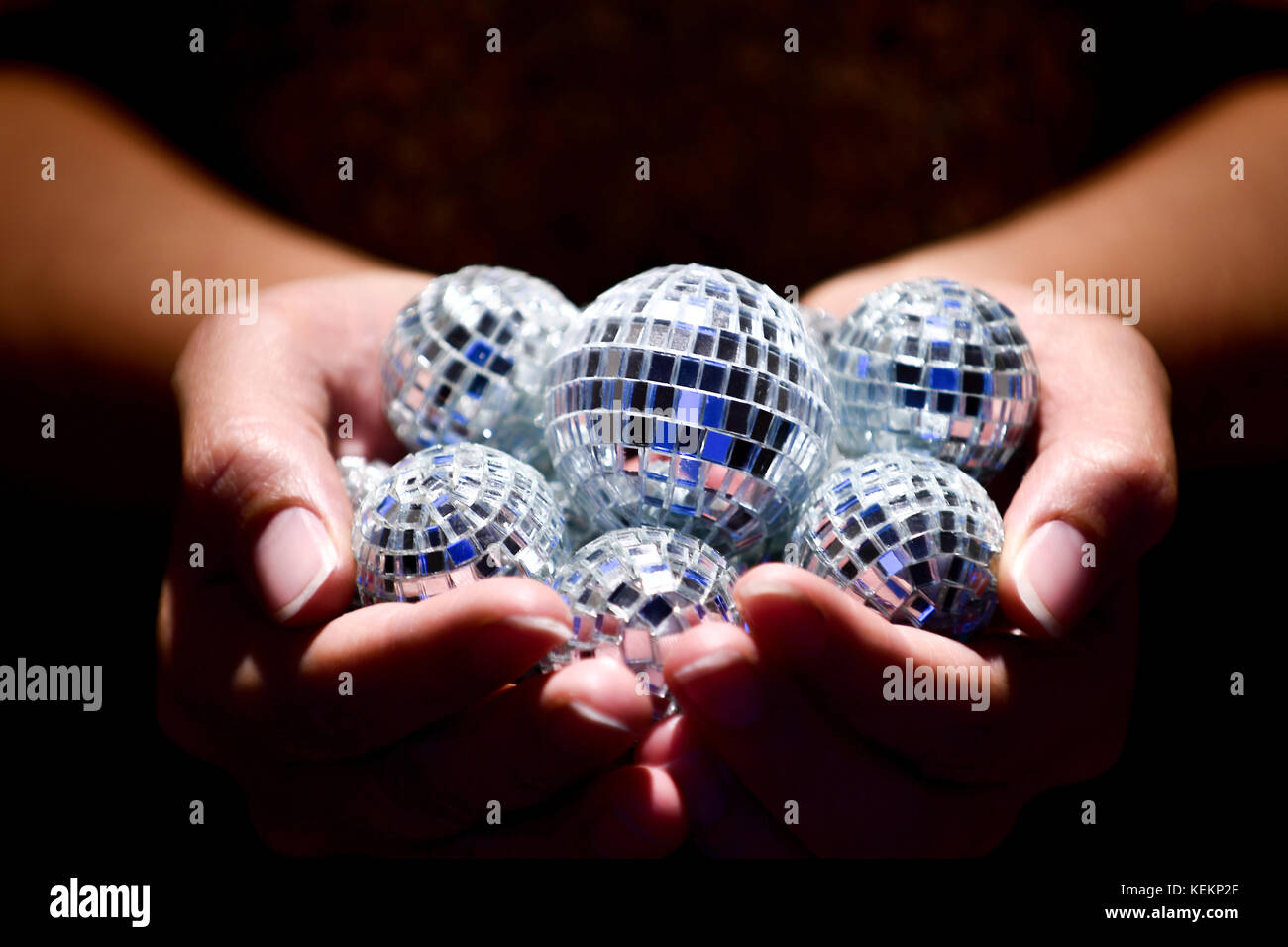 Close up della donna azienda discoballs sotto un faretto Foto Stock