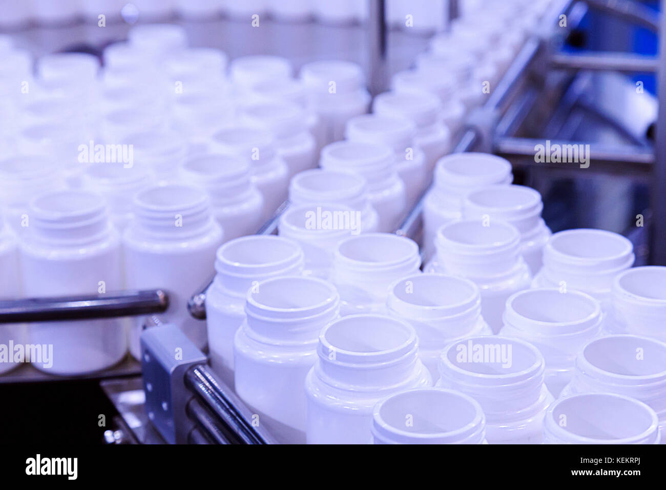 Bottiglia di plastica bianca sulla linea di produzione del nastro alla macchina di riempimento in fabbrica. Il fuoco selettivo. Foto Stock