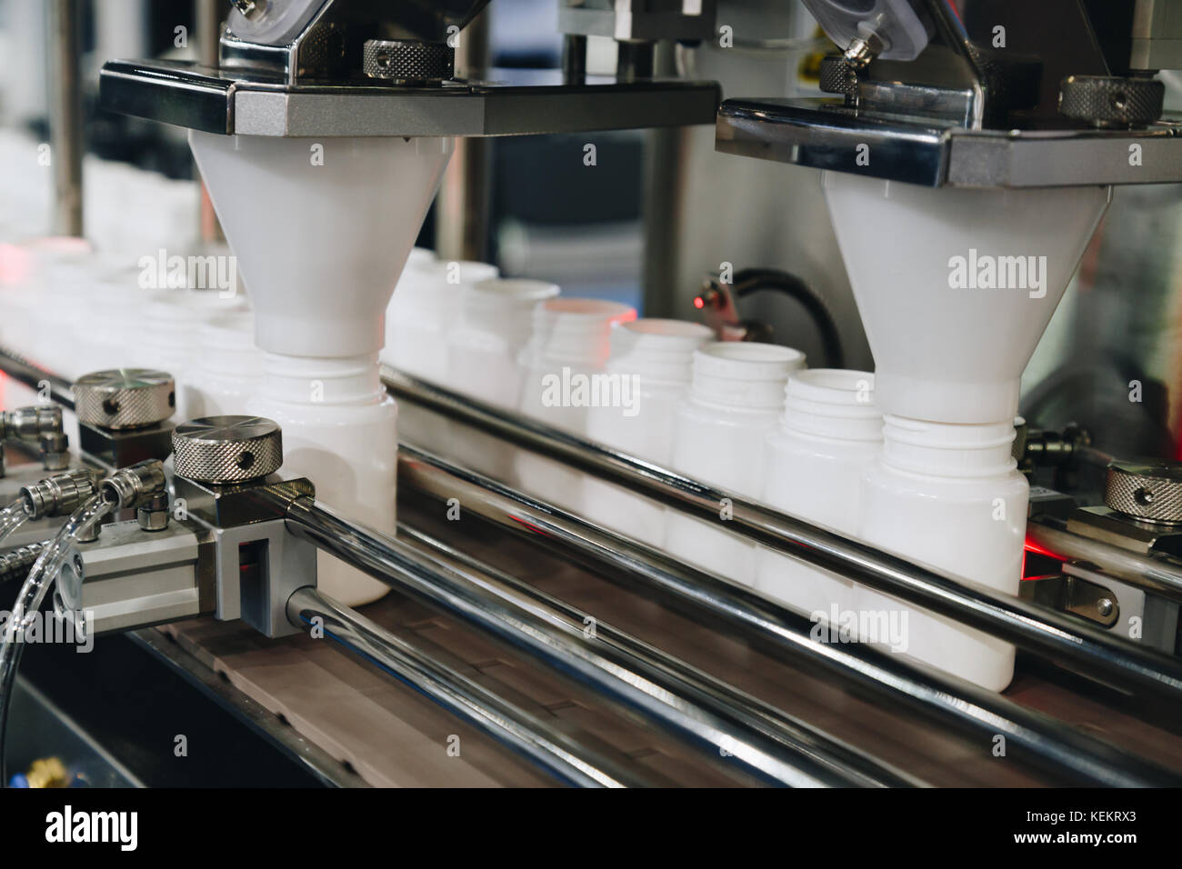 Bianco di bottiglie di plastica sulla linea di produzione del nastro alla macchina di riempimento in fabbrica. Il fuoco selettivo. Foto Stock