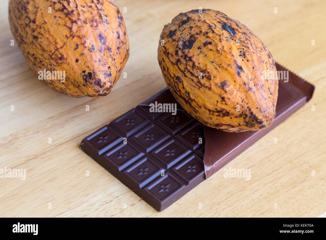 Giallo fresco baccelli di cacao e cioccolato bar sul tavolo di legno dello sfondo. Foto Stock