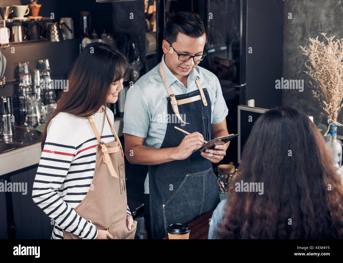 Asia barista cameriere prendere ordine dal cliente nel negozio di caffè,due cafe proprietario iscritto ordine di bevanda al bancone bar,cibo e bevande concetto aziendale,servizio Foto Stock