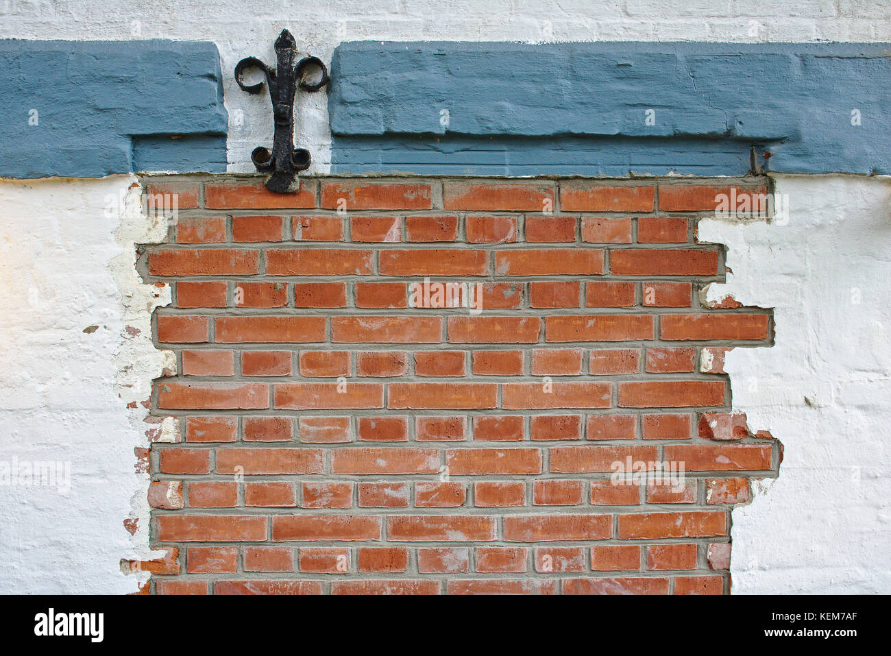 In mattoni rossi con muro di ferro battuto decorazione, parzialmente intonacata di bianco e blu-grigio gesso Foto Stock