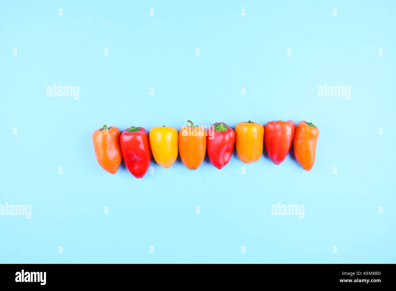 Rosso, arancione, giallo paprika trendy su sfondo blu. copia spazio, piatto stile laici. colorato la dieta e il cibo sano concetto. Foto Stock