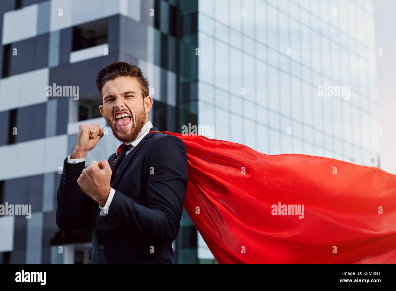 Un imprenditore in un costume da supereroe esulta. Foto Stock