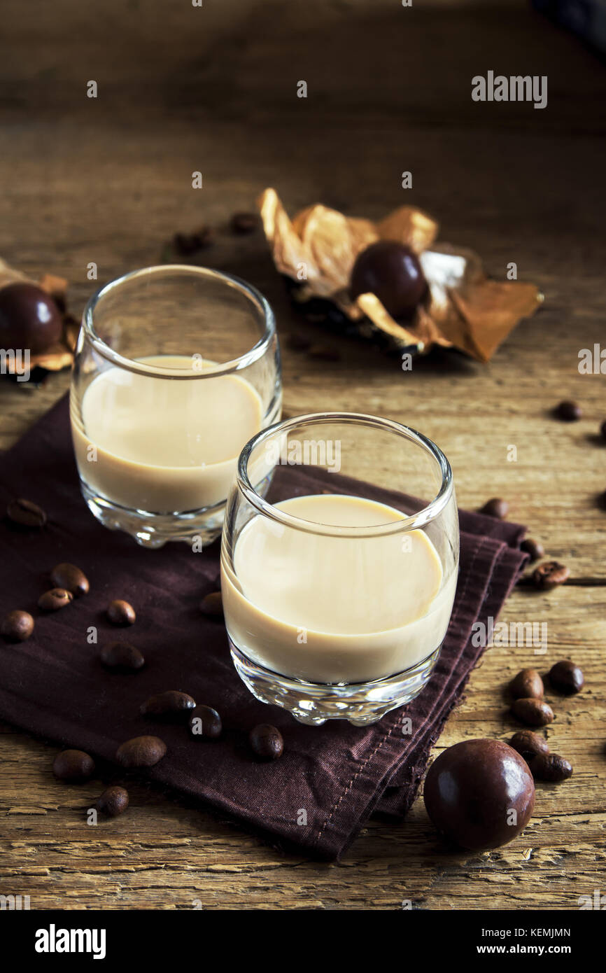 Irish cream liquore al caffè con ghiaccio, cioccolatini e chicchi di caffè più rustico sfondo di legno - in casa di festa bere alcool Foto Stock