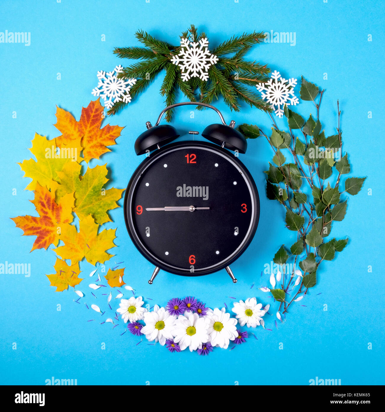 Che rappresentano le stagioni dell'anno attraverso la sveglia e il materiale naturale su uno sfondo blu. autunno vista superiore Foto Stock