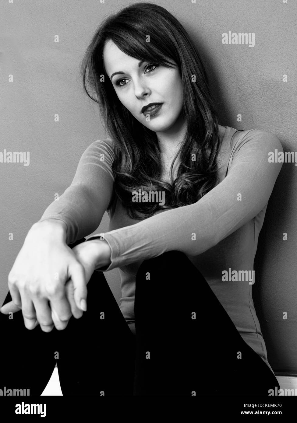 Ritratto di un triste pensieroso giovane donna cercando infelice e interessata in bianco e nero monocromatico Foto Stock