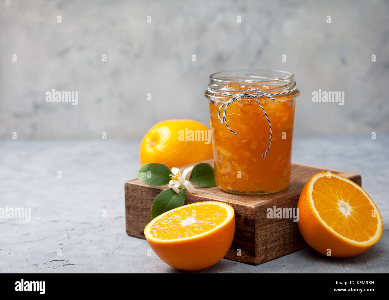 Orange inceppamento in un vasetto di vetro, arance fresche su un cemento grigio sfondo Foto Stock