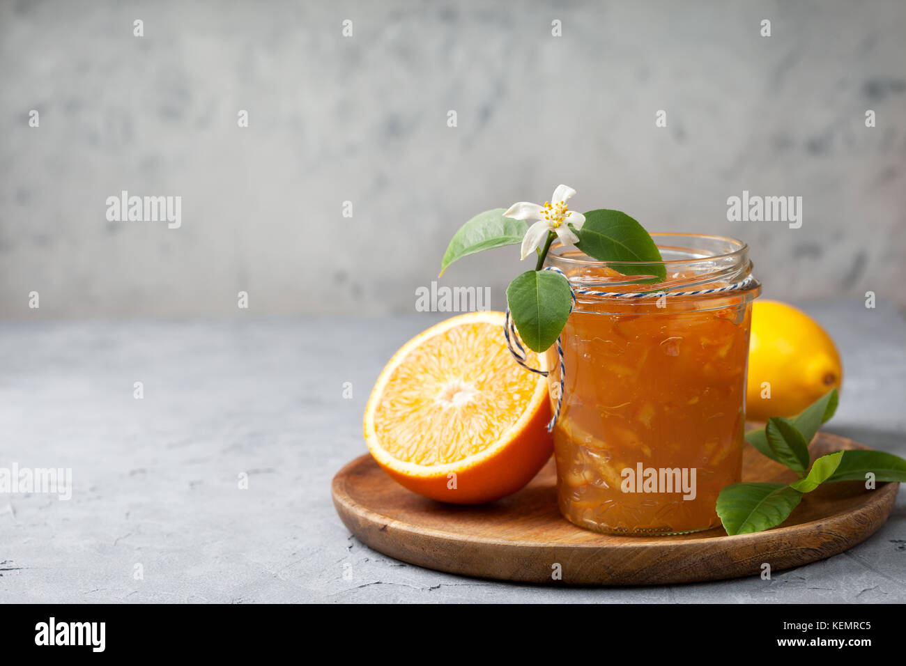 Orange inceppamento in un vasetto di vetro, arance fresche su un cemento grigio sfondo Foto Stock