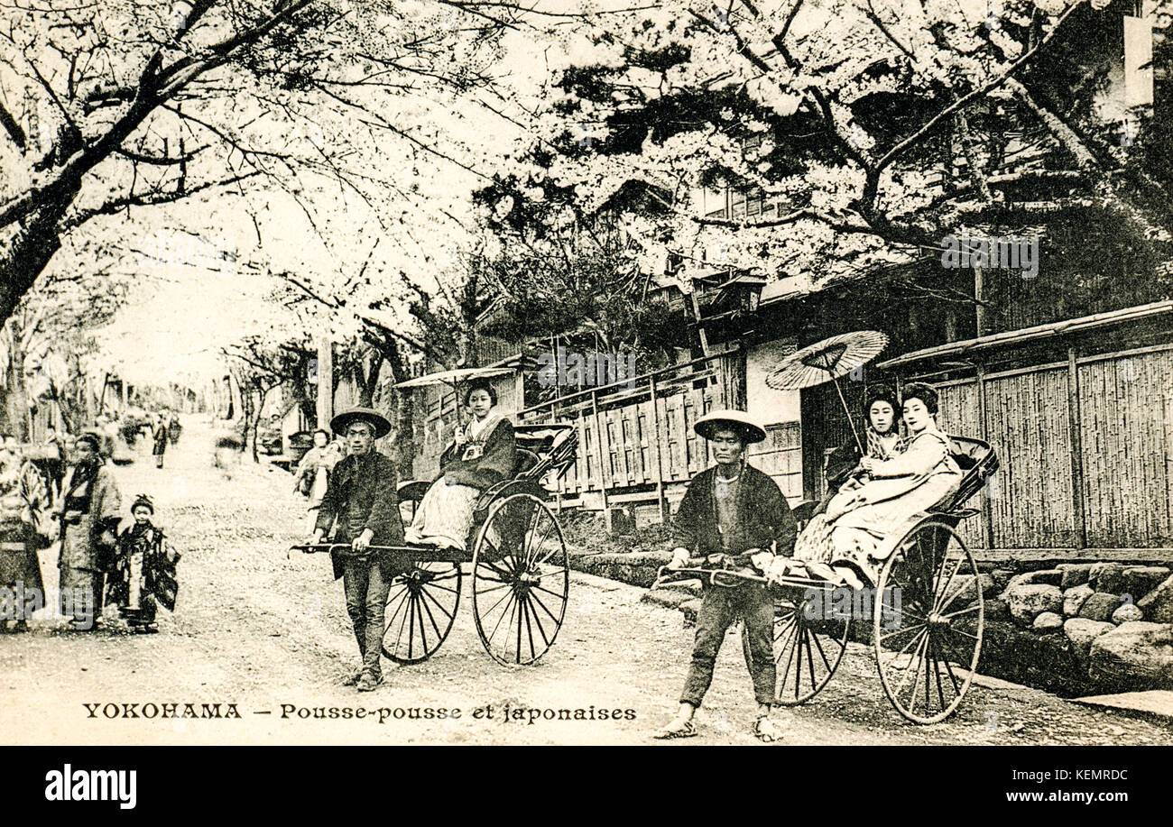 Giappone, Yokohama. Vintage, circa 1900, in bianco e nero cartolina di risciò in street, con donne in kimono seduto in rickshaw. Foto Stock