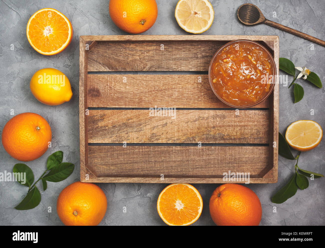 Orange inceppamento in un vasetto di vetro, arance fresche su un cemento grigio Sfondo. vista da sopra Foto Stock