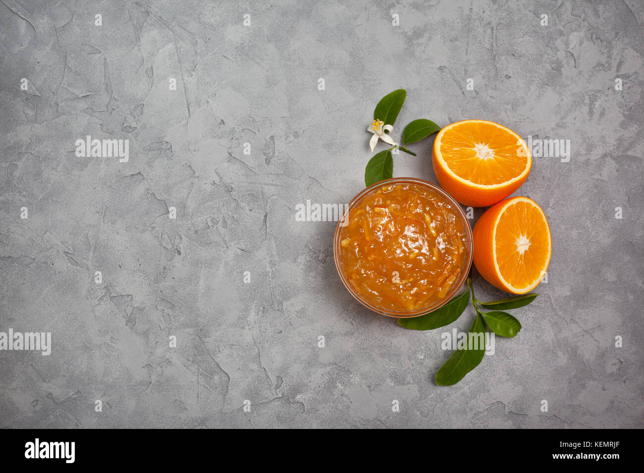 Orange inceppamento in un vasetto di vetro, arance fresche su un cemento grigio Sfondo. vista da sopra Foto Stock
