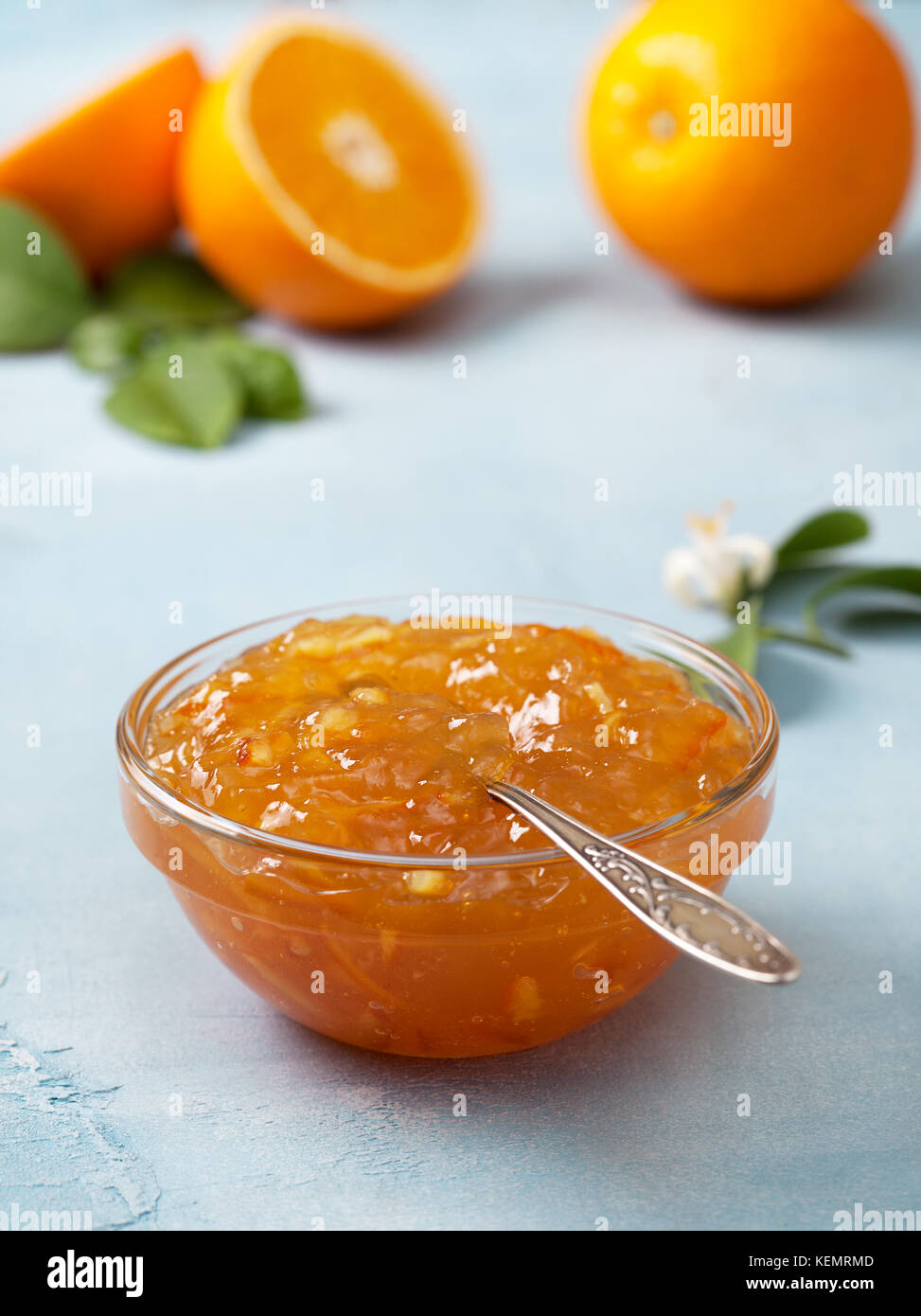 Marmellata di arancia in una ciotola di vetro, arance fresche su uno sfondo blu. Foto Stock