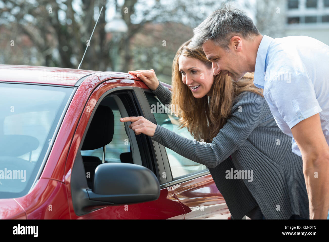 Coppia felice cercando nuove auto rossa in auto salon Foto Stock