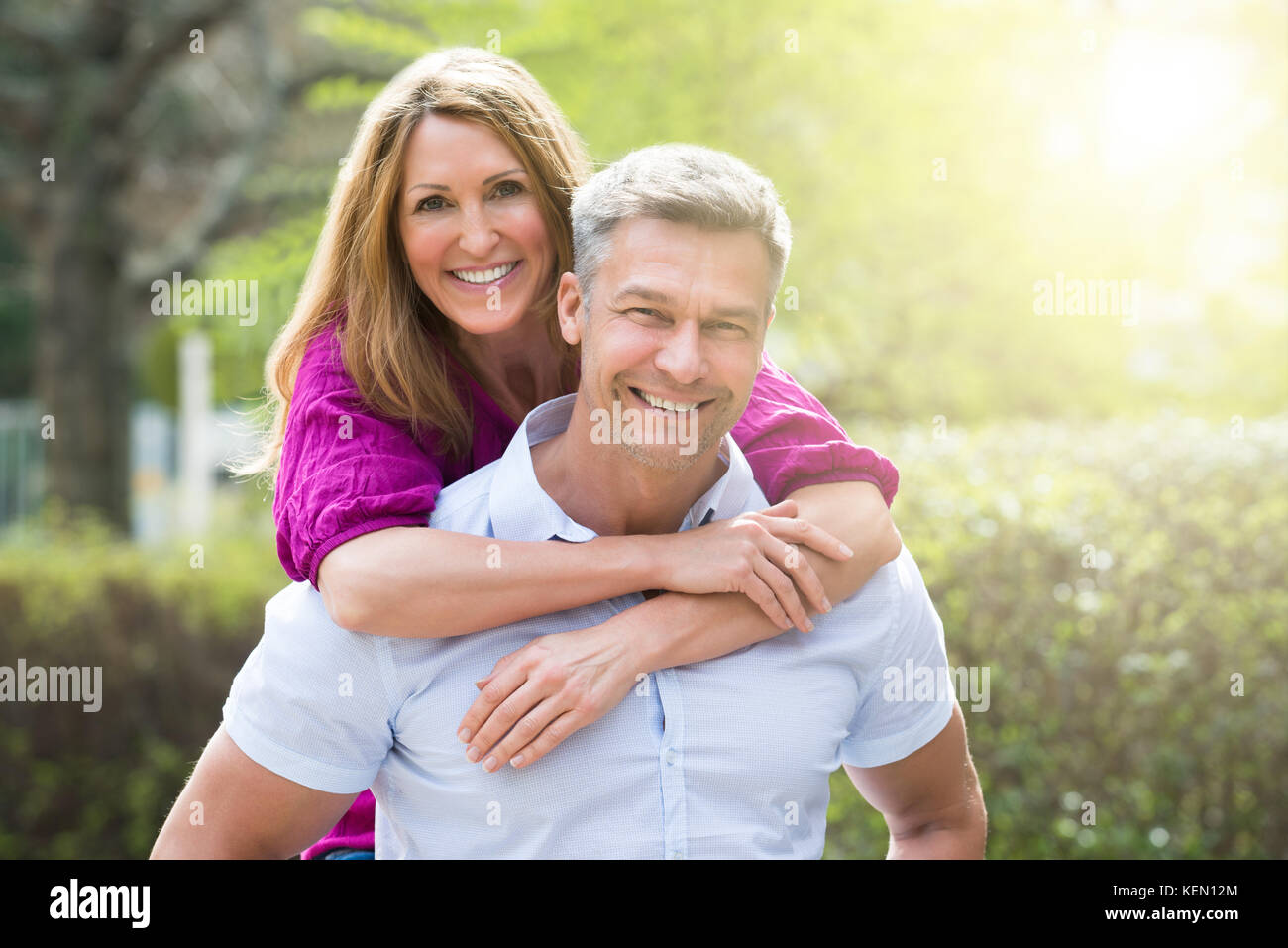 Ritratto di donna felice abbracciando il marito da dietro Foto Stock