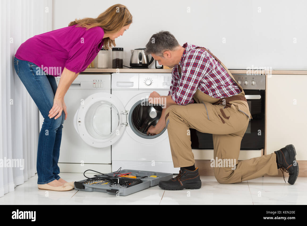 Donna che guarda Repairman controllo macchina lavatrice in cucina Foto  stock - Alamy