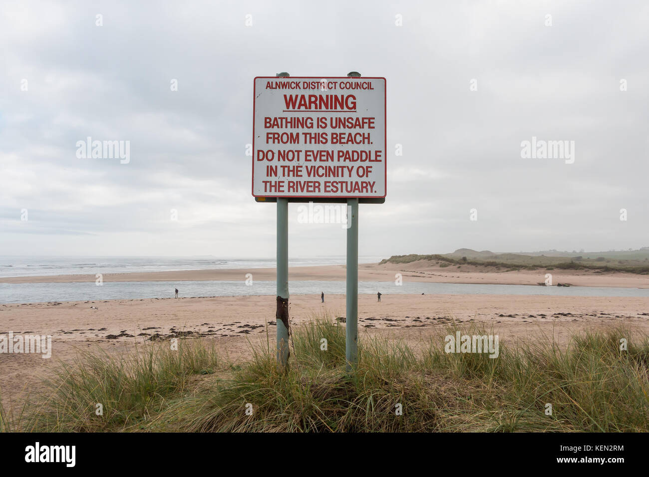 Segno di avvertimento non sicuri condizioni di balneazione nel fiume Tagliamento a Alnmouth, Northumberland, Regno Unito con la foce e la spiaggia in background con spazio di copia Foto Stock