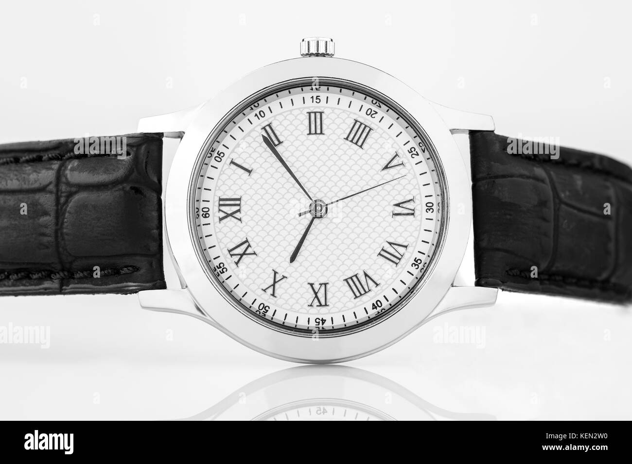 Close up di chrome orologio da polso con numeri romani e cinturino in cuoio nero girato in studio Foto Stock
