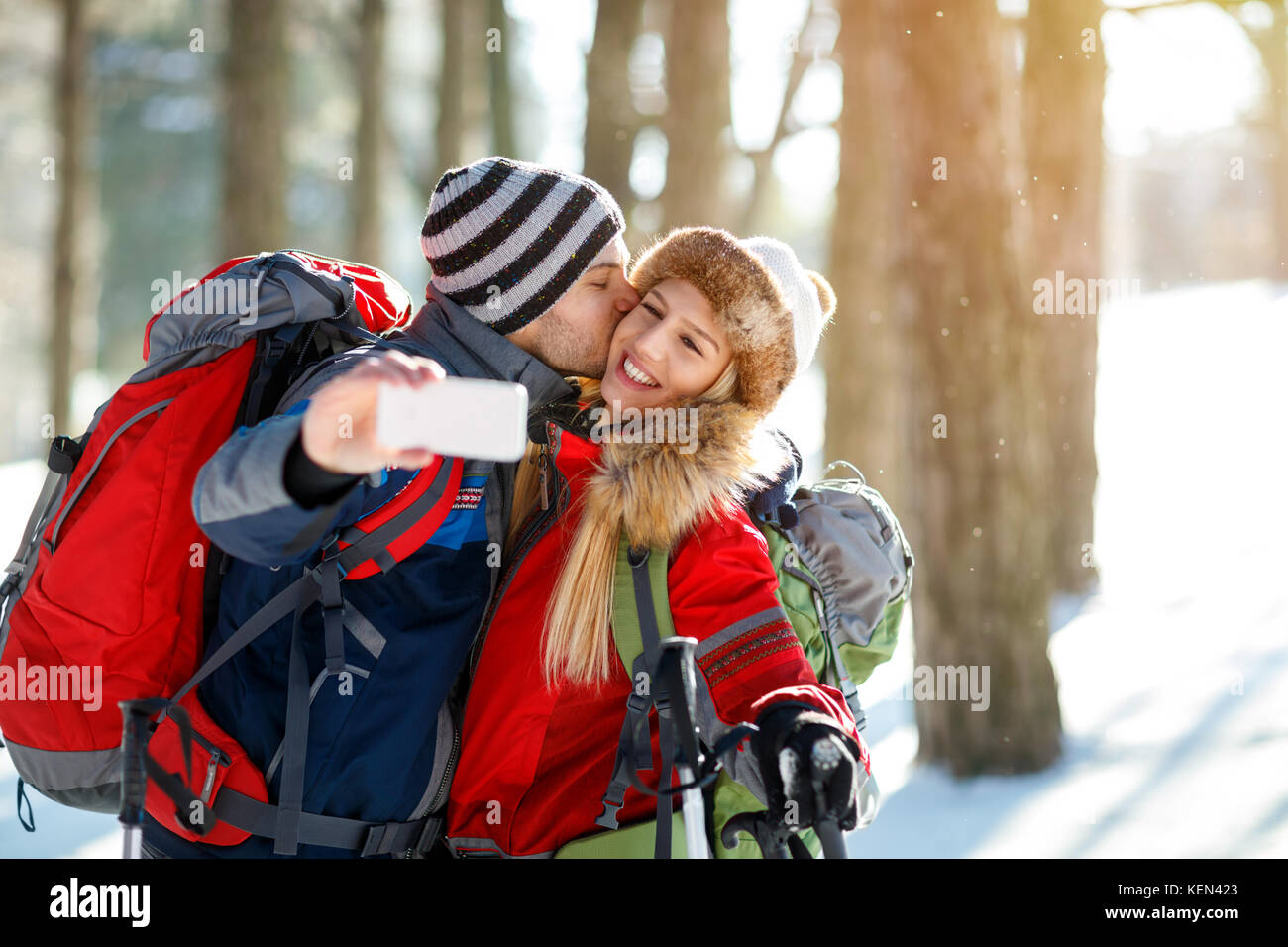 Alpinista maschio baciare la sua ragazza mentre rendendo selfie per le vacanze invernali Foto Stock