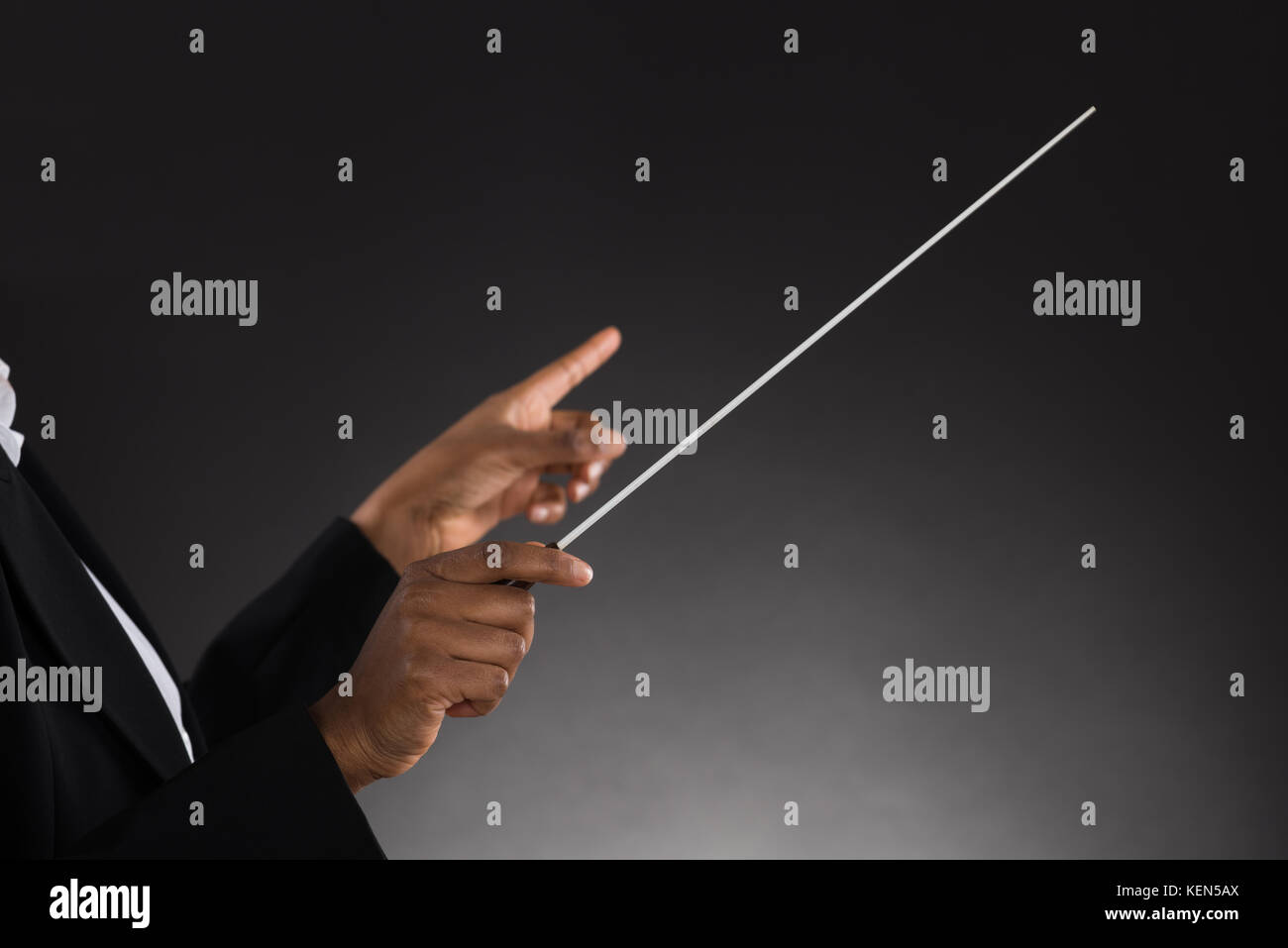 Close-up di femmine della orchestra holding baton su sfondo nero Foto Stock