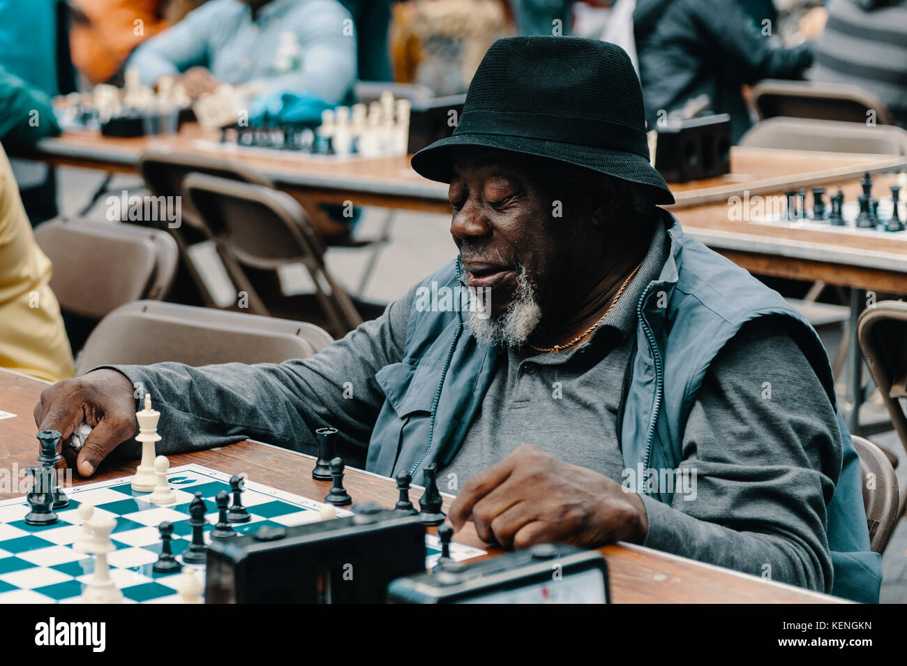 Vecchio americano africano uomo senior di trascorrere il tempo libero giocando a scacchi a central park con un multietnica gruppo di amici. Foto Stock