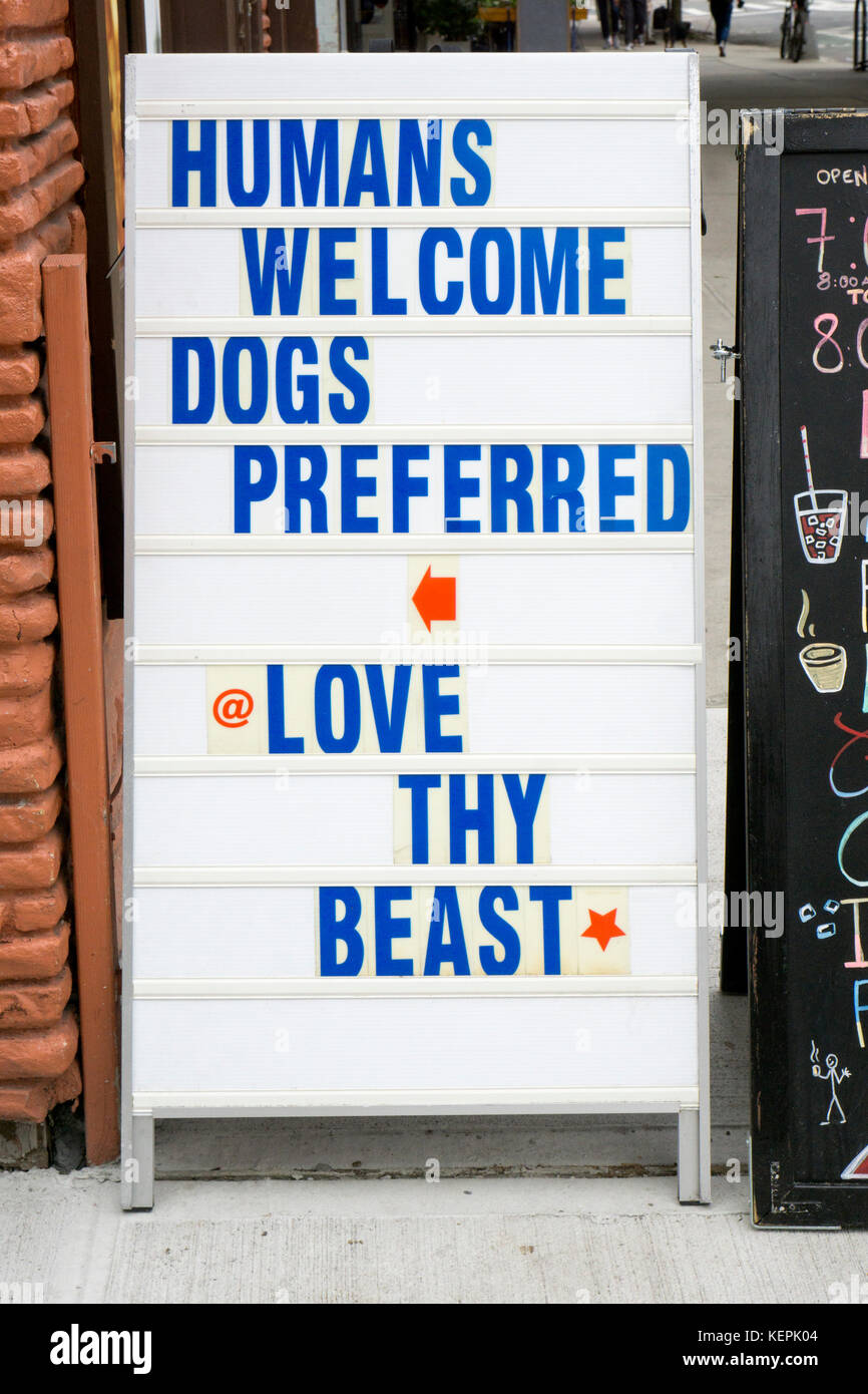 Un divertente di firmare al di fuori di un negozio di produzione di alimenti per animali da compagnia nell'East Village sostenendo il proprietario del negozio di preferenza per i cani sulle persone. Nella città di New York. Foto Stock
