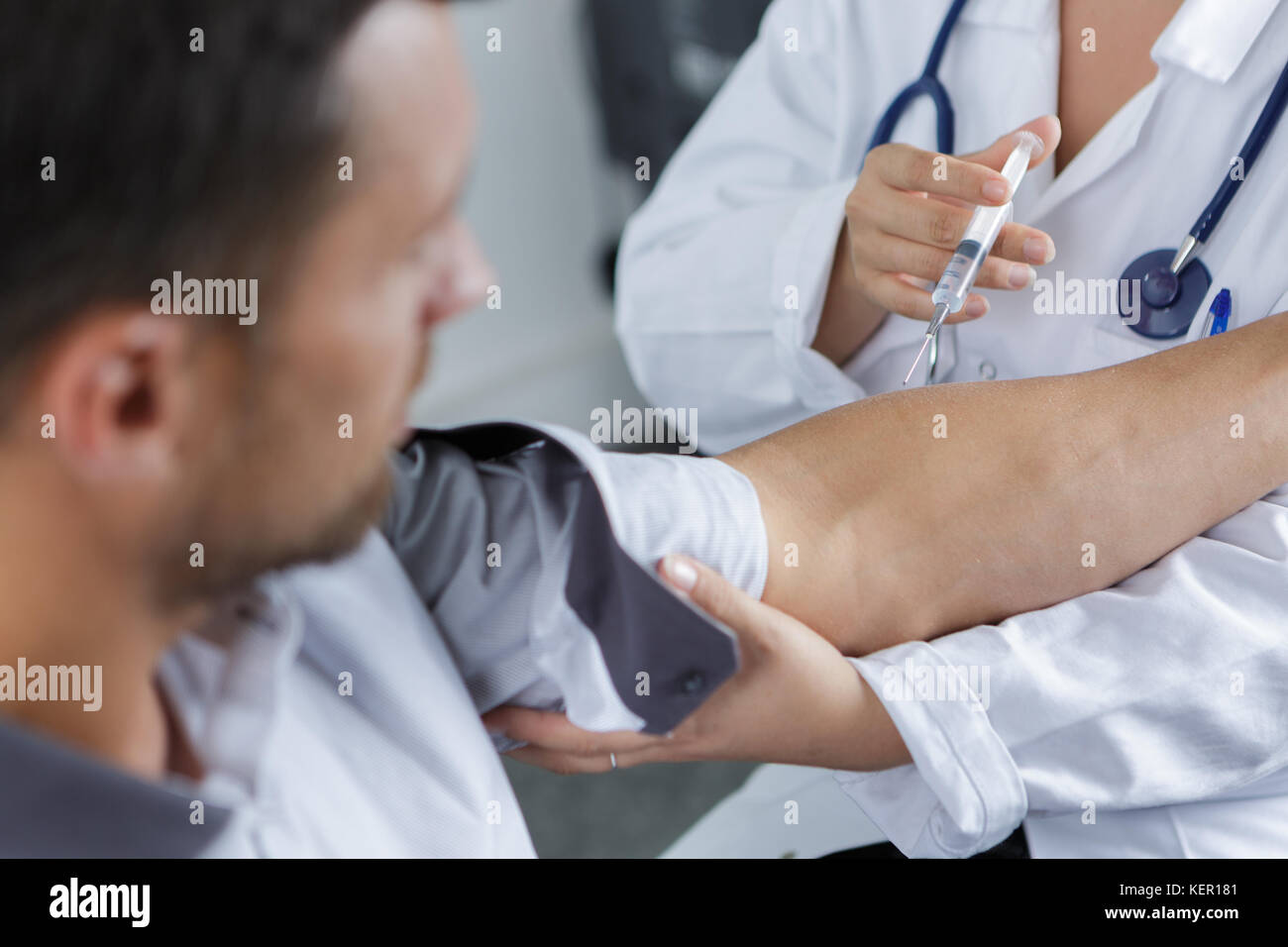 Medico dà una iniezione intramuscolare in braccio maschio Foto Stock