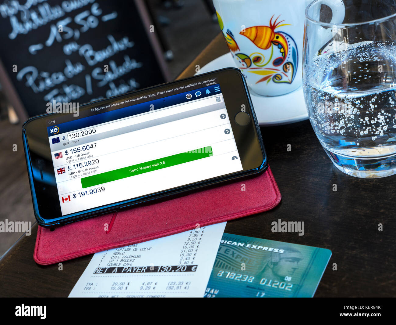 Moneta di Scambio app sulla schermata di iPhone nel ristorante francese di pagamento di bollette situazione all'estero, la carta Amex & euro bill sul tavolo. (Carta alterata in modo sicuro) Foto Stock