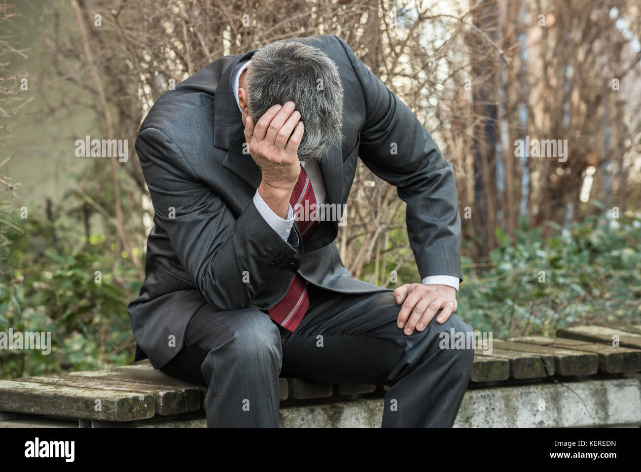 Imprenditore triste seduta sul banco di prova all'aperto e di avere mal di testa Foto Stock