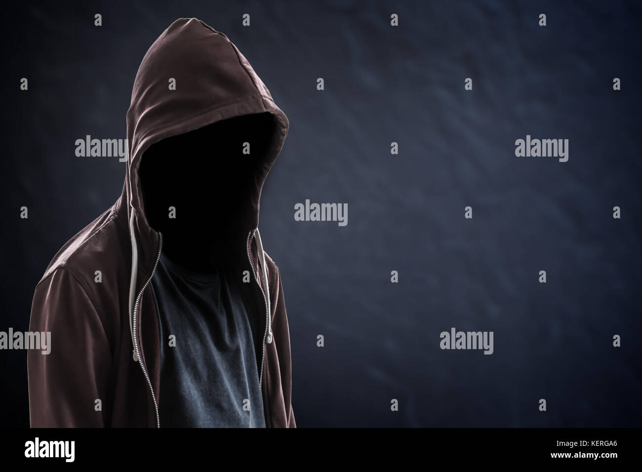 Silhouette dell'uomo con cappuccio e volto sullo sfondo nero scuro con spazio per le copie, concetto criminale o hacker Foto Stock