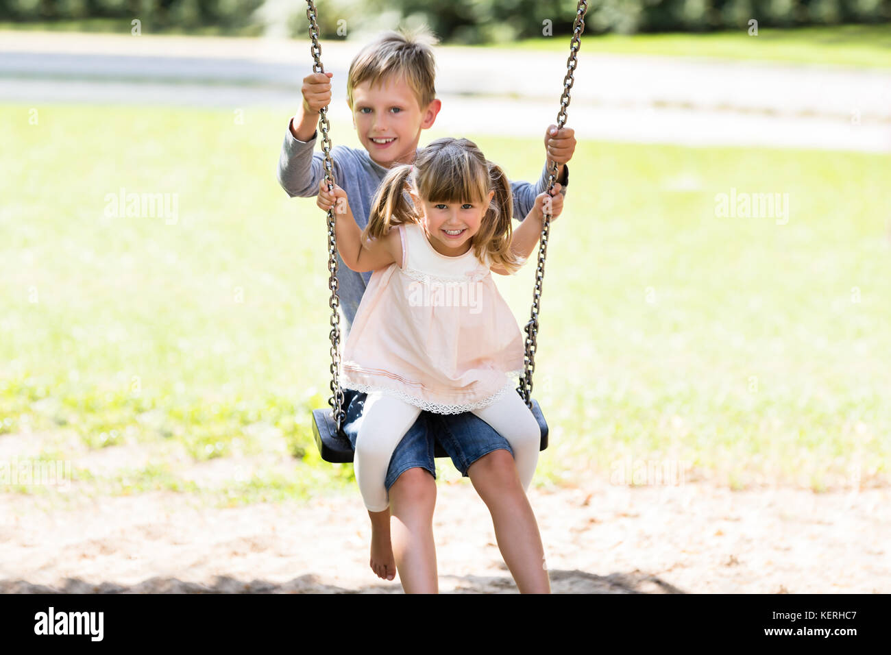 Due bambini felici godendo sull'altalena nel Parco Foto stock - Alamy
