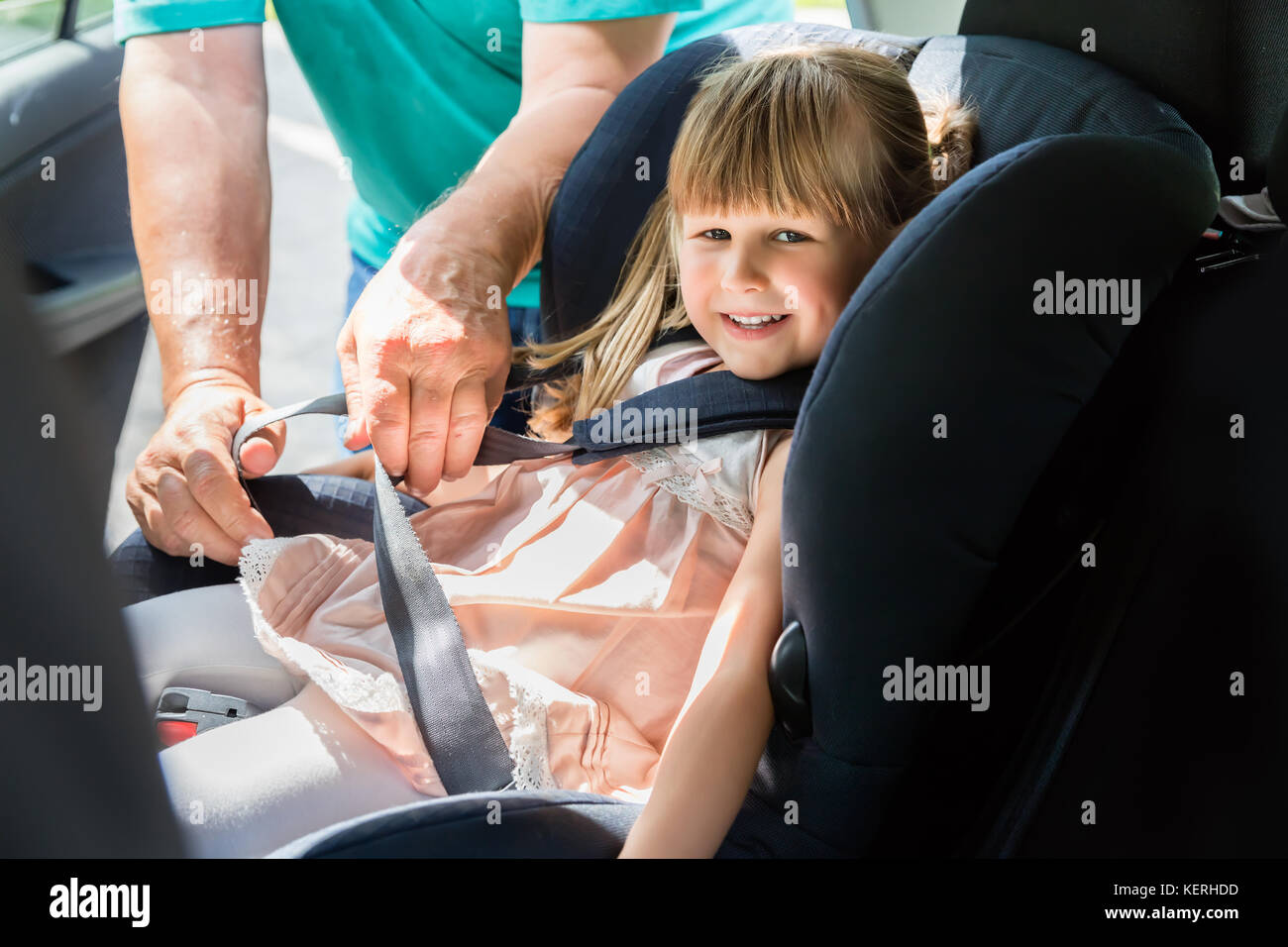 L'uomo imbozzamento cintura di sicurezza per il bambino nel seggiolino di  sicurezza in auto Foto stock - Alamy