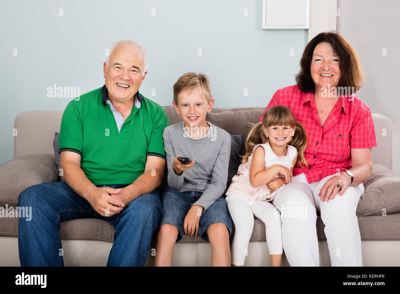 Multi generazioni la famiglia con due bambini guardando film in tv seduti sul divano insieme Foto Stock