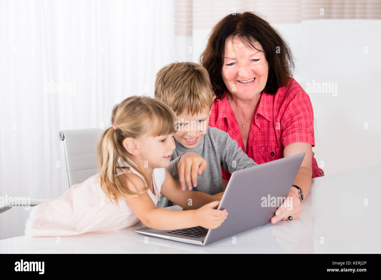 Felice Babysitter giocando con i bambini sul computer portatile Foto Stock