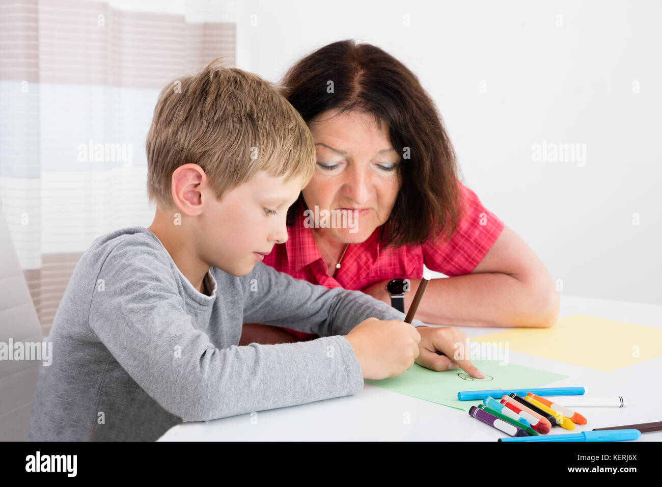 Babysitter disegno su carta con il ragazzo a casa Foto Stock