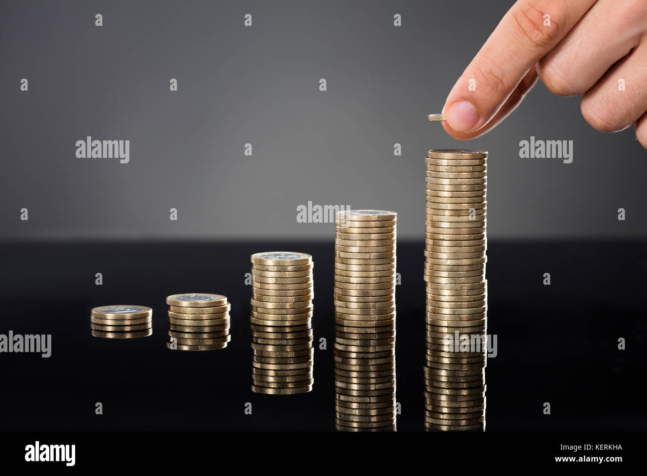 Close-up di una persona di monete di impilamento sulla scrivania su sfondo grigio. investimento concetto di crescita Foto Stock