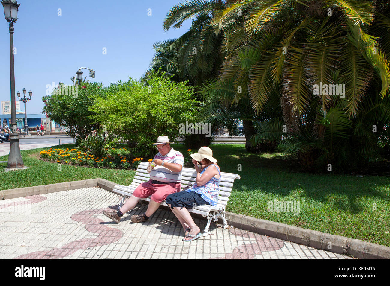 Coppia di mezza età seduta e mangiare su una panchina nel parco a Cadice un antico porto della città nel sud-ovest della Spagna Foto Stock