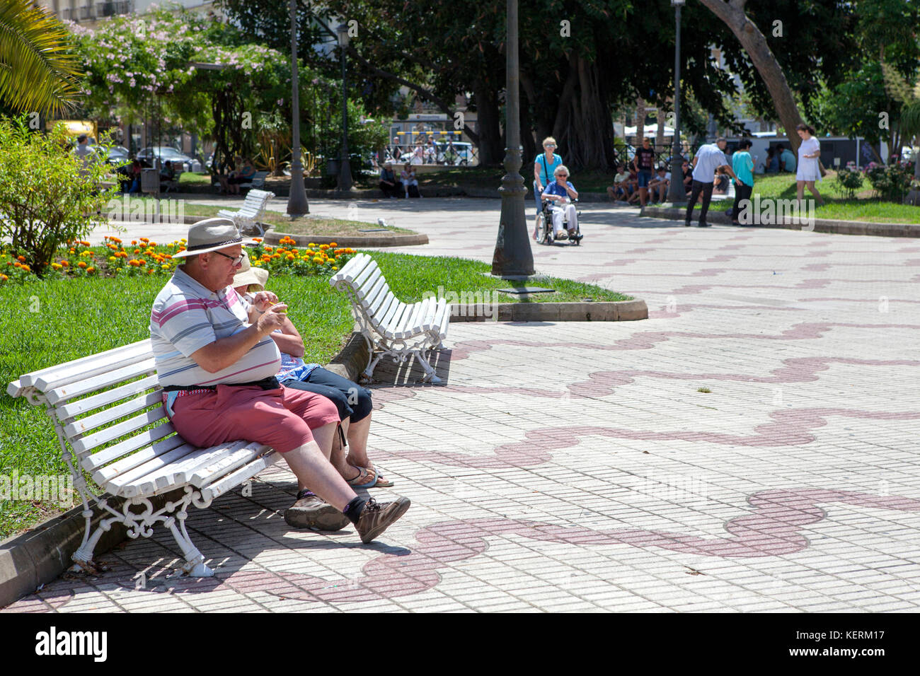 Coppia di mezza età seduta e mangiare su una panchina nel parco a Cadice un antico porto della città nel sud-ovest della Spagna Foto Stock