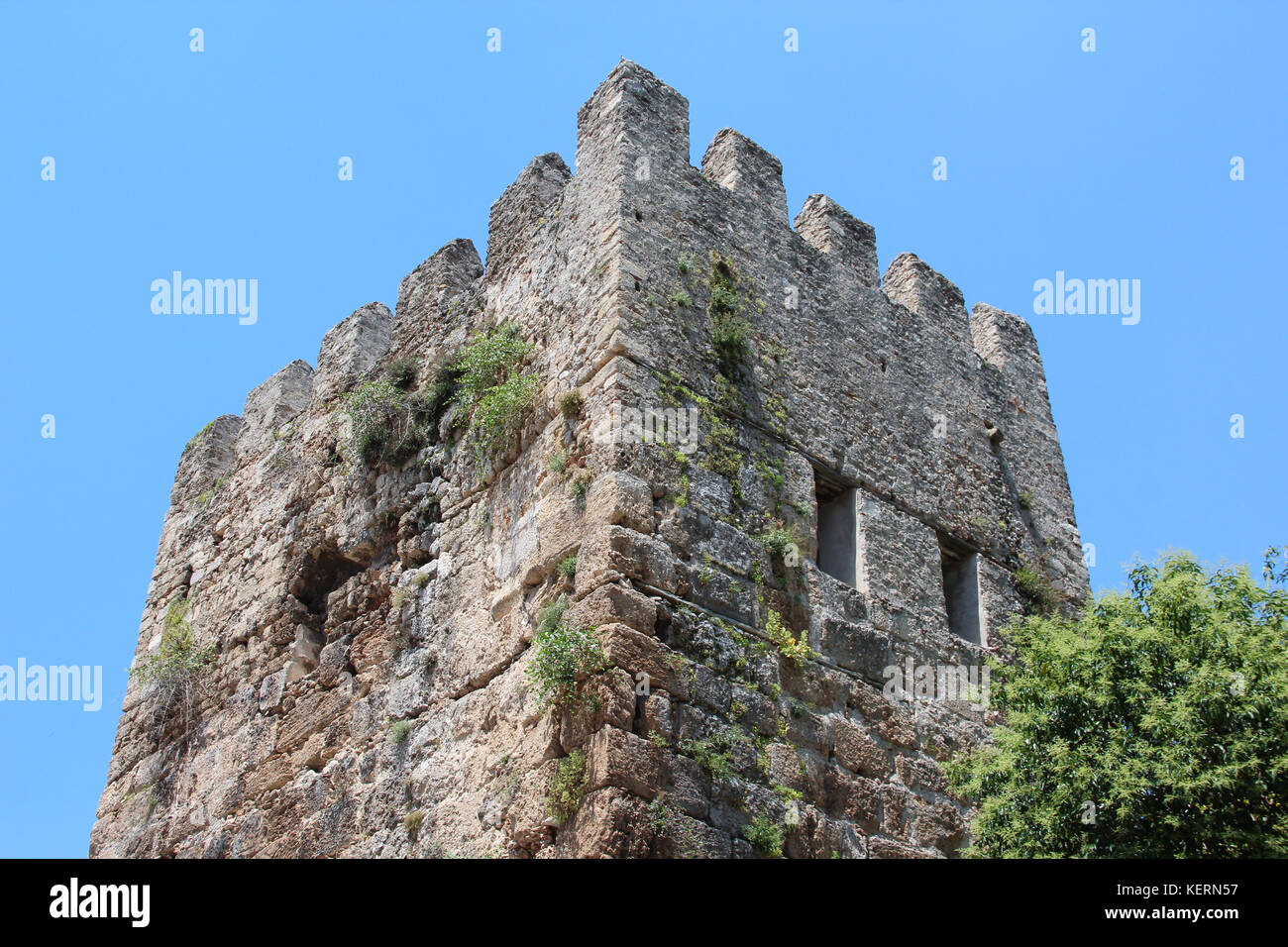 L antica torre merlata all'antica la Porta di Adriano a Antalya, Turchia. sullo sfondo del cielo blu e il verde degli alberi. Foto Stock