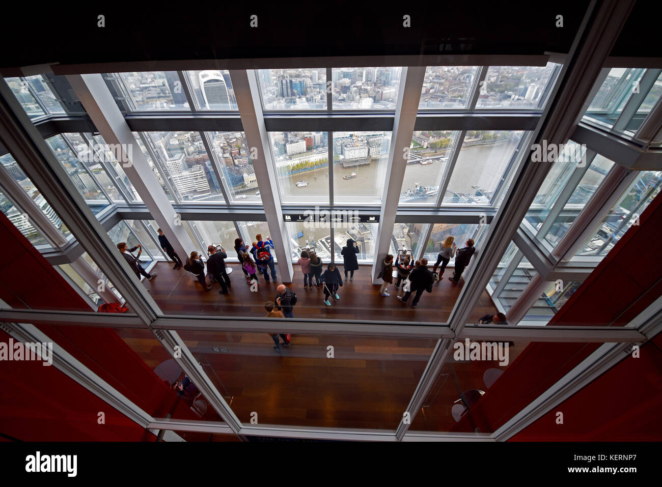 I visitatori del Shard guardando la vista dal piano di visualizzazione. Londra visibile sotto al di fuori delle finestre. Foto Stock