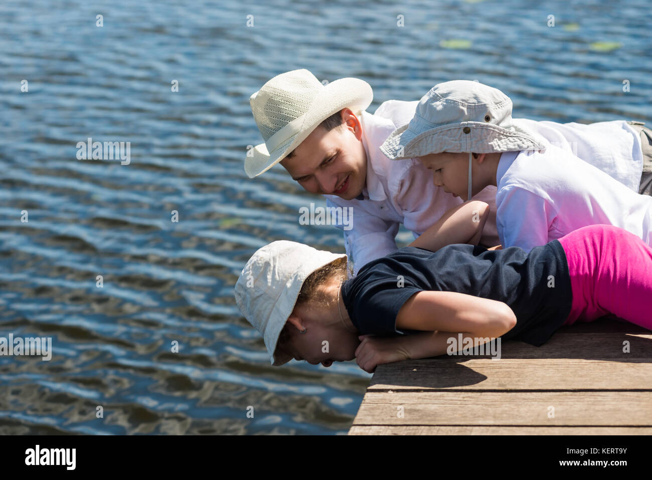 Padre con figli giacciono e guardare un bel lago e il pesce in acqua Foto Stock