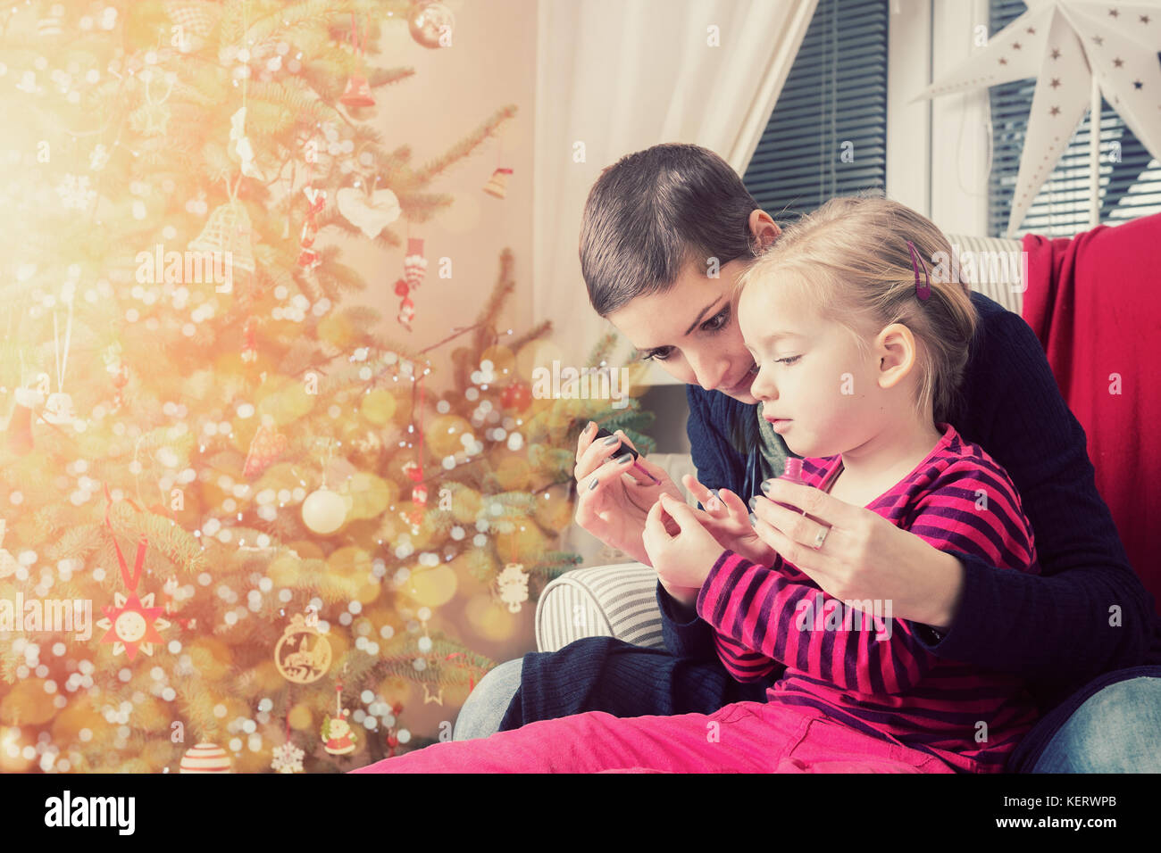 Madre e figlia divertendosi pittura dito unghie sul giorno di Natale Foto Stock